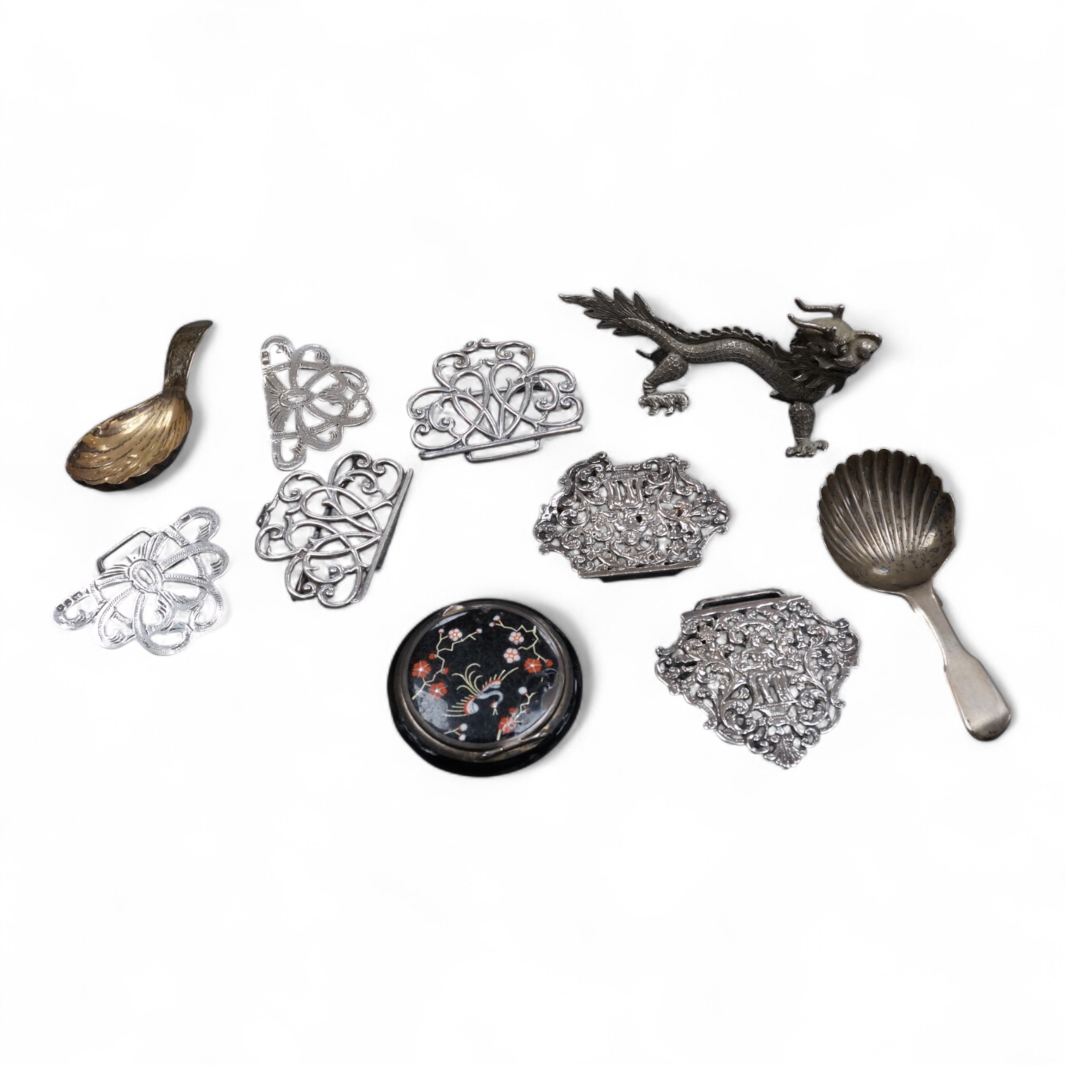 A group of small collectable silver including a white metal dragon menu holder? by Wang Hing, 92mm, two 19th century caddy spoons, three assorted belt buckles and a 1920's silver and enamel pill box(a.f), import marks fo